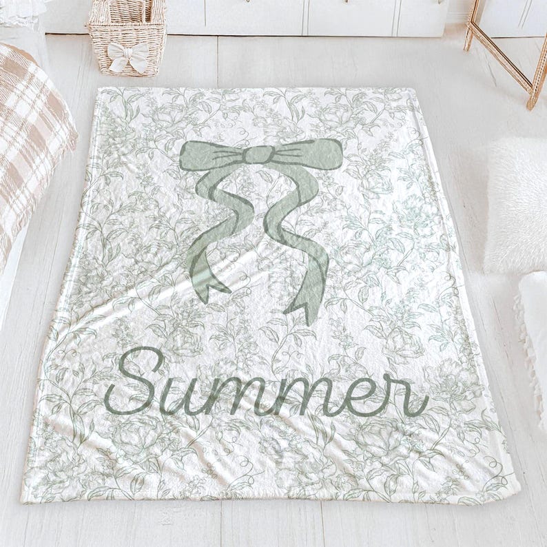 My Personalized Sage Green Bow Toile Name Blanket features a classic olive toile print with delicate flowers and birds on a crisp white background, topped with a big coquette-style bow and your custom name in an elegant script below. Soft feminine and beautifully detailed, it’s perfect for babies, kids, teens and adults. Great for sleepover favors, hospital or coming-home blankets, announcement photos, dorm rooms, teen bedrooms, Christmas, birthdays, sisters, newborn keepsakes and new parents
