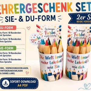 Può includere: Un set regalo per insegnanti composto da due contenitori cilindrici riempiti con matite colorate. I contenitori sono avvolti in carta con il testo in tedesco 'Die Welt braucht mehr Lehrkräfte wie Sie' e 'Die Welt braucht mehr Lehrkräfte wie dich'.