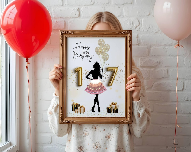 May include: A framed print with a gold-colored frame, featuring a black silhouette of a person in a dress, the number "17", and the words "Happy Birthday". Gold balloons and gift boxes are also included in the design. A red and a pink balloon are in the background.