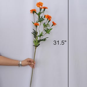 K&ouml;nnte beinhalten: Ein einzelner Stiel k&uuml;nstlicher Ringelblumen mit leuchtend orangefarbenen Bl&uuml;ten und gr&uuml;nen Bl&auml;ttern. Der Stiel ist 80 cm lang und eignet sich perfekt f&uuml;r Blumengestecke und Heimdekoration.