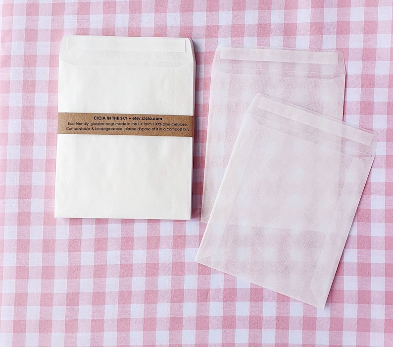 May include: Two white paper envelopes on a pink and white gingham background. The smaller envelope has a brown label with the text "CICIA IN THE SKY etsy.cicla.com Eco-friendly glassine bags made in the UK from 100% pine cellulose. Compostable & biodegradable, please dispose of it in a compost bin."