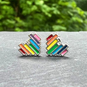 May include: A pair of rainbow heart-shaped earrings. The earrings are made of silver metal and have a rainbow enamel design.
