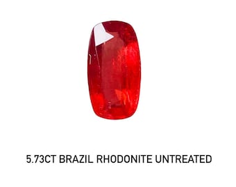 May include: A vibrant red rhodonite gemstone from Brazil. The rectangular-shaped stone is untreated and weighs 5.73 carats. The gem has a polished surface with a reflective quality, and is set against a white background.