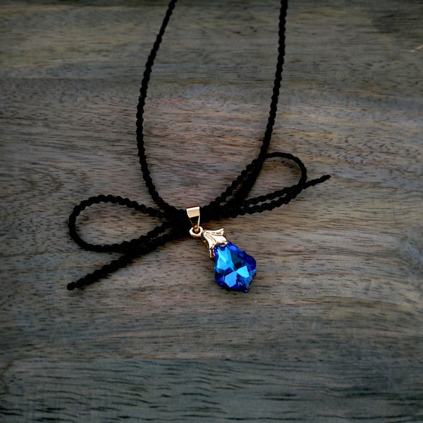 Zwarte choker ketting met strik en blauwe kristallen goutte barokke hanger, minimalistische boho choker, ketting flirterige stijl.