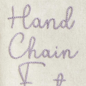 May include: Close-up of a cream-colored fabric with the embroidered words "Hand Chain". The text is in a lavender color, with a cursive font. The embroidery thread has a textured, rope-like appearance.