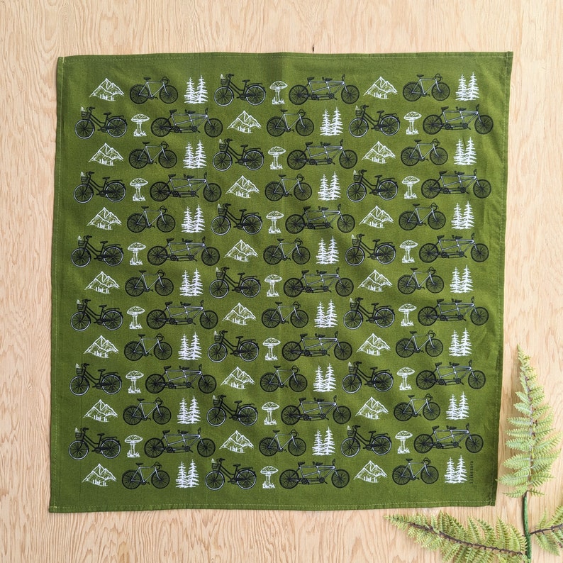 Pu&ograve; includere: Bandana verde con un motivo ripetitivo di biciclette nere e alberi bianchi. La bandana &egrave; realizzata in morbido tessuto di cotone.