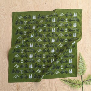 Pu&ograve; includere: Bandana verde con un motivo ripetuto di biciclette e alberi in bianco e nero.