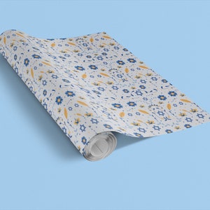 K&ouml;nnte beinhalten: Eine Rolle wei&szlig;es Geschenkpapier mit einem blauen und gelben Blumenmuster mit Davidsternen.