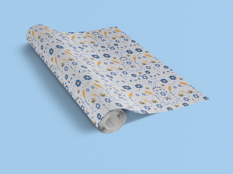 K&ouml;nnte beinhalten: Eine Rolle wei&szlig;es Geschenkpapier mit einem blauen und gelben Blumenmuster mit Davidsternen.