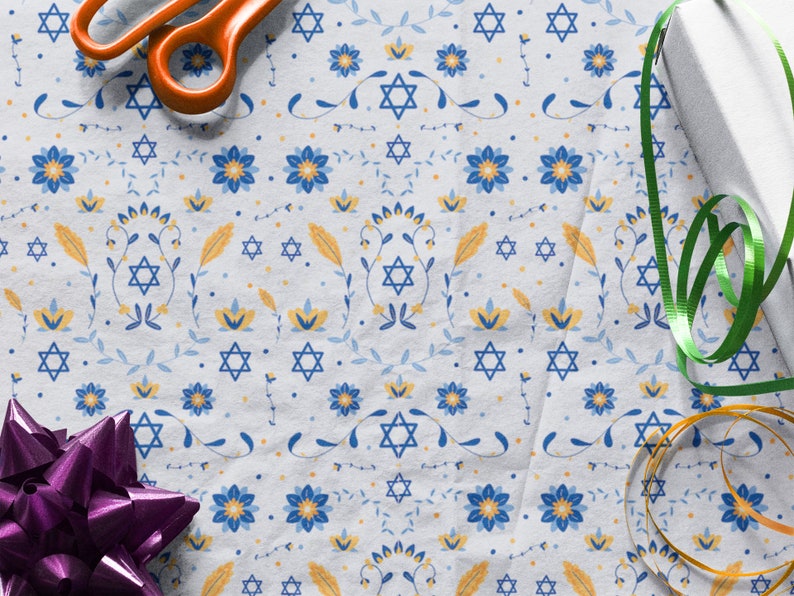 K&ouml;nnte beinhalten: Wei&szlig;es Geschenkpapier mit einem blauen und gelben Blumenmuster und einem sich wiederholenden Davidstern-Design. Das Papier ist mit einem gr&uuml;nen Band, einem goldenen Band und einer lila Schleife verziert.