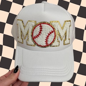 May include: White baseball cap with a gold glitter MOM patch and a red and white baseball graphic.