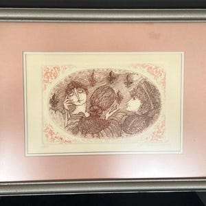 May include: A framed print of a vintage illustration featuring three people with intricate details. The print is in shades of brown and cream, with a pink mat and a silver frame.
