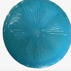 Puede incluir: Un objeto redondo y transl&uacute;cido de color azul claro, con un patr&oacute;n radial que emana del centro. El objeto parece estar hecho de un material flexible, con una superficie ligeramente texturizada. La forma general es circular, y el color es un azul vibrante y fr&iacute;o.