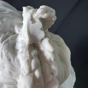 May include: Close-up of a white marble sculpture with intricate details. The sculpture features a flowing, organic form with a textured surface.