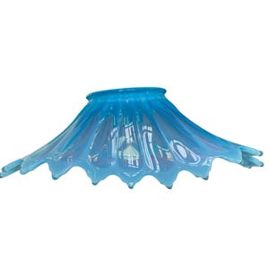 Puede incluir: Pantalla de l&aacute;mpara de cristal azul claro con borde ondulado y festoneado. La pantalla tiene forma acampanada, como de campana, y est&aacute; hecha de cristal transl&uacute;cido. El color pasa de un azul m&aacute;s oscuro en la parte superior a un azul m&aacute;s claro, casi blanco, en los bordes.