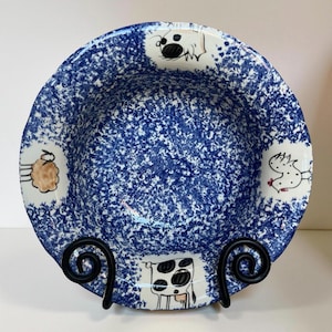 Puede incluir: Un cuenco de cerámica azul y blanco con un esmalte moteado. El cuenco presenta ilustraciones pintadas a mano de animales de granja, incluyendo una vaca, una gallina, una oveja y un perro.