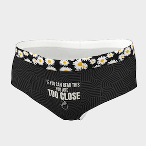 May include: Black underwear with a daisy pattern along the top edge. The main body features a repeating geometric design and the text "IF YOU CAN READ THIS YOU ARE TOO CLOSE" with a hand graphic.
