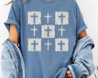 May include: A blue t-shirt with a white distressed pattern of nine crosses.