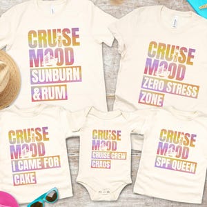 May include: Off-white t-shirts and a onesie with colorful text that reads "CRUISE MOOD" followed by various phrases: "SUNBURN & RUM", "ZERO STRESS ZONE", "I CAME FOR CAKE", "CRUISE CREW CHAOS", and "SPF QUEEN".