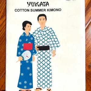May include: A sewing pattern envelope titled YUKATA COTTON SUMMER KIMONO featuring an illustration of two figures wearing traditional Japanese garments. One figure wears a blue floral yukata with a red obi, and the other wears a white grid-patterned yukata.