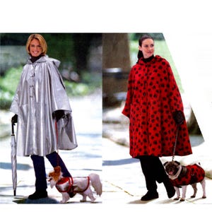 May include: Two women wearing hooded rain capes, one silver and one red with black heart patterns. Each woman is walking a dog wearing a matching coat. The silver cape has a button closure and the woman is holding an umbrella.