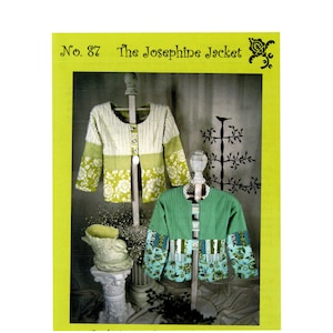 Puede incluir: Imagen de dos chaquetas Josephine. Una es crema y verde con mangas florales, la otra es verde con mangas florales. Las chaquetas se exhiben en soportes de madera contra un fondo con elementos decorativos. El texto "No. 87 The Josephine Jacket" está en la parte superior.
