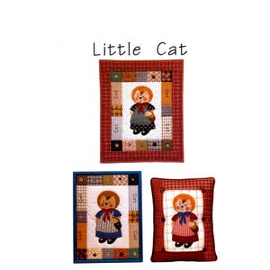 May include: Three handmade fabric items featuring a cat character. The items include two framed wall hangings and a pillow. The cat character has orange fur, a red bow, and a basket. The text "Little Cat" is above the items.
