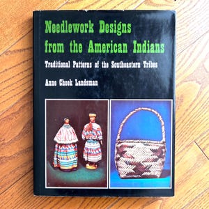 May include: A book titled "Needlework Designs from the American Indians" with the subtitle "Traditional Patterns of the Southeastern Tribes" by Anne Cheek Landsman. The cover features images of dolls and a woven basket.