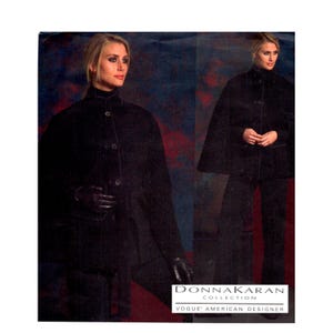 May include: A black cape-style jacket with a high collar, front button closures, and a matching tie belt, paired with black trousers and dark gloves. The text DONNA KARAN COLLECTION VOGUE AMERICAN DESIGNER is printed at the bottom right.