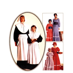 Puede incluir: Tres mujeres y dos niñas vestidas con trajes de peregrinos. Las mujeres llevan vestidos largos con cuellos y gorros blancos. Las niñas llevan vestidos similares con cuellos y gorros blancos. Las mujeres sostienen libros y un plato.