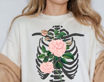 May include: White t-shirt with a black ribcage design and pink roses growing from it.