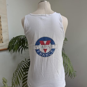 May include: White tank top with a blue and red logo that says "Vuarnét France".
