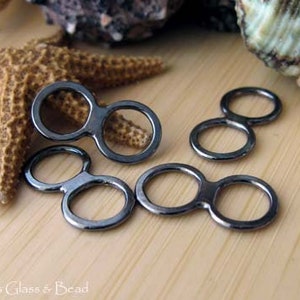 May include: Three black metal double loop connectors. The connectors are in the shape of a figure eight with two circles.