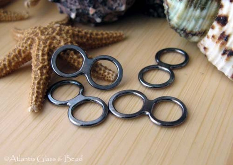 May include: Three black metal double loop connectors. The connectors are in the shape of a figure eight with two circles.