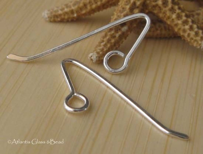 May include: Two silver earring hooks with a loop at the end. The hooks are made of metal and are designed to be used with earrings.