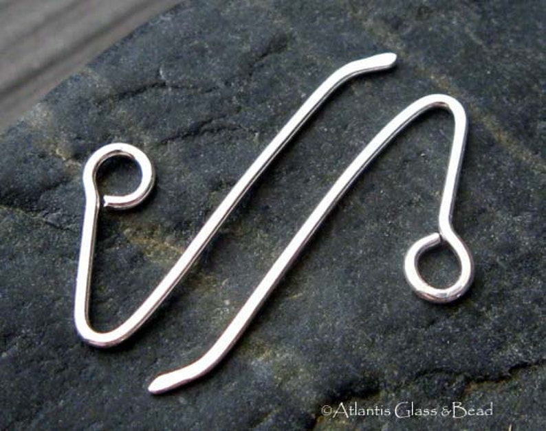 May include: Two silver-toned metal earring hooks with a loop at the end. The hooks are bent into a V-shape.