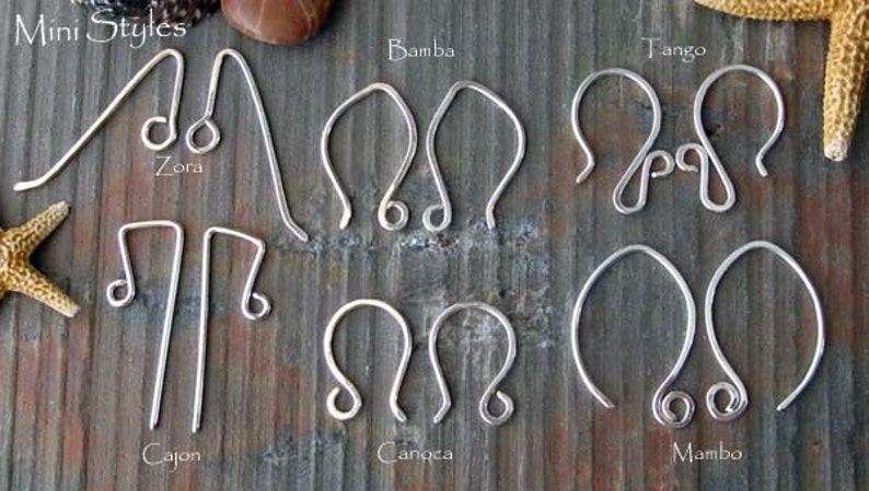 May include: A close-up of ten different styles of silver earring hooks. The hooks are arranged in two rows of five. The hooks are labelled with names such as "Zora", "Bamba", "Tango", "Cajon", "Canocha", and "Mambo".