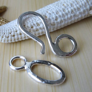 May include: Two silver-toned metal clasps, one with a hook and a ring, the other with a ring and a loop.