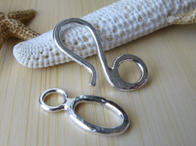 May include: Two silver-toned metal clasps, one with a hook and a ring, the other with a ring and a loop.