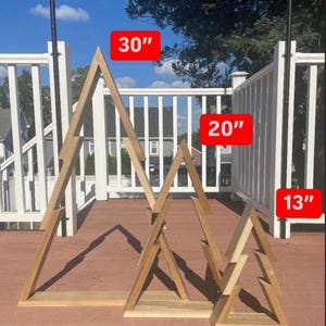 May include: Three wooden triangle shelves in the shape of a Christmas tree. The largest shelf is 30 inches tall, the middle shelf is 20 inches tall, and the smallest shelf is 13 inches tall.