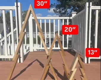 May include: Three wooden triangle shelves in the shape of a Christmas tree. The largest shelf is 76 cm tall, the middle shelf is 51 cm tall, and the smallest shelf is 33 cm tall.