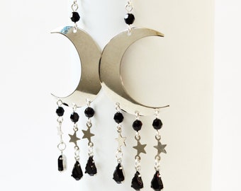 May include: Silver crescent moon earrings with black bead and star accents.