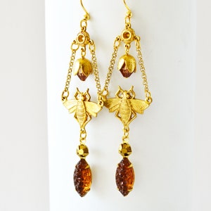 May include: Gold tone earrings with a bee design, amber coloured glass teardrop dangles, and a flower detail.