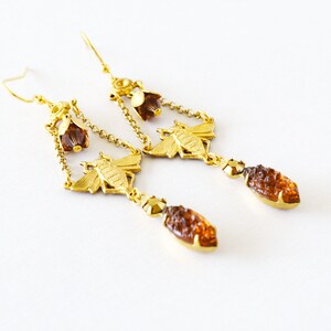 May include: Gold tone dangle earrings with a bee design and amber coloured glass beads.
