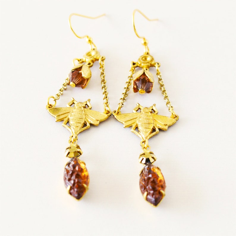 May include: Gold tone earrings featuring a bee design and amber coloured glass beads.