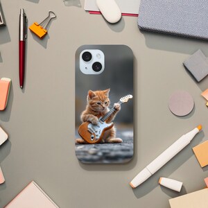 May include: A phone case with a picture of a ginger cat playing an electric guitar. The cat is wearing a black collar and has a white chest. The guitar is brown and has a white pickguard.