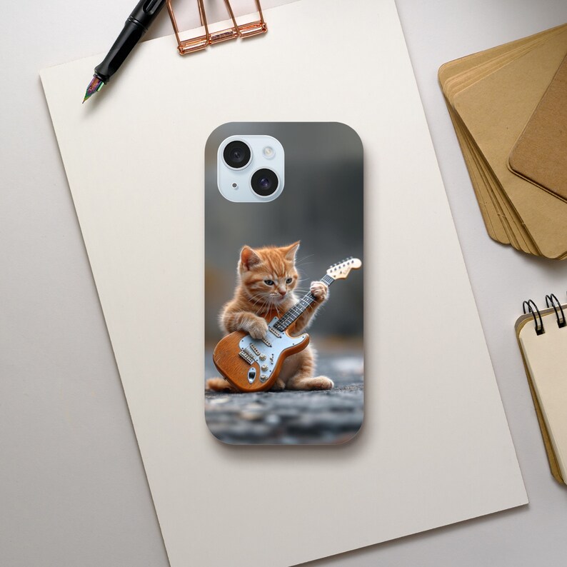 May include: A phone case with a cute orange tabby kitten playing an electric guitar. The kitten is sitting on a gray background.