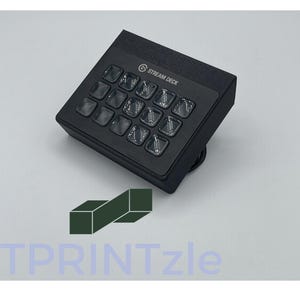 May include: A black Stream Deck with 15 customizable buttons. The buttons are backlit and have a clear plastic cover. The Stream Deck is a popular tool for streamers and content creators.