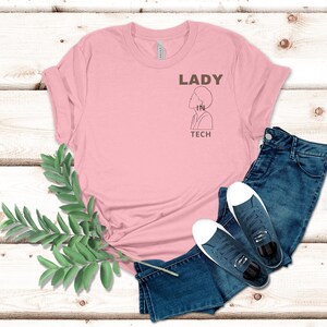 May include: Pink t-shirt with the text "LADY IN TECH" and a line drawing of a woman's head and shoulders.
