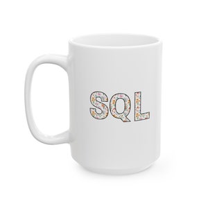May include: White ceramic mug with a floral design spelling out the word "SQL".